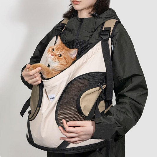 Person wearing a black jacket with a beige pet carrier holding an orange cat on a white background